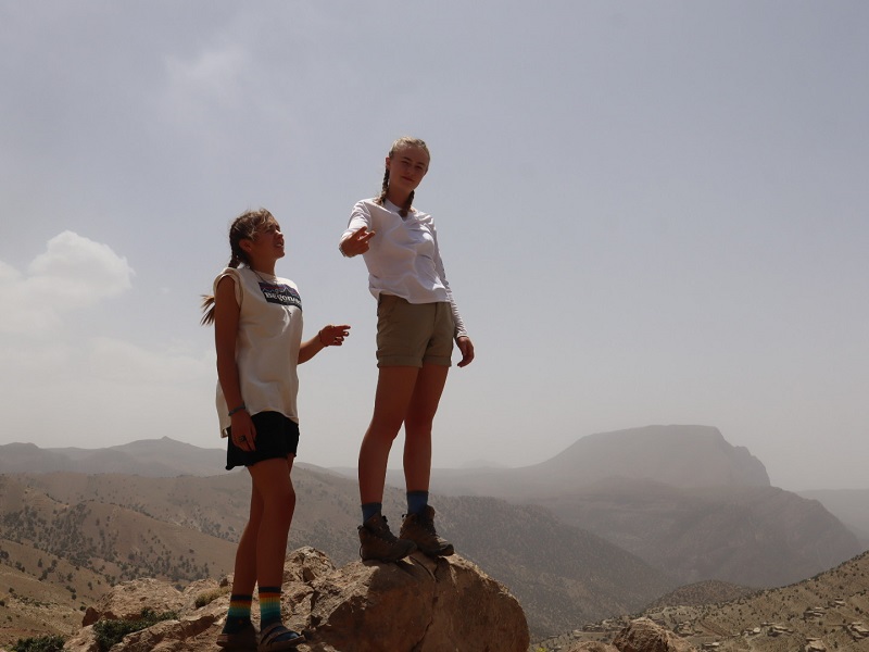 two students in front of blue grey sky