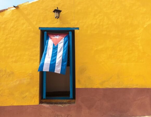 cuban flag hanging in window with bright yellow wall